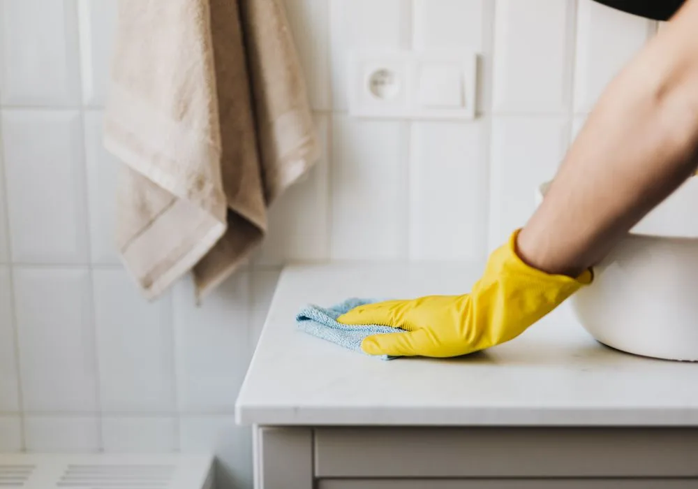 A cleaner wiping a white bathroom surface