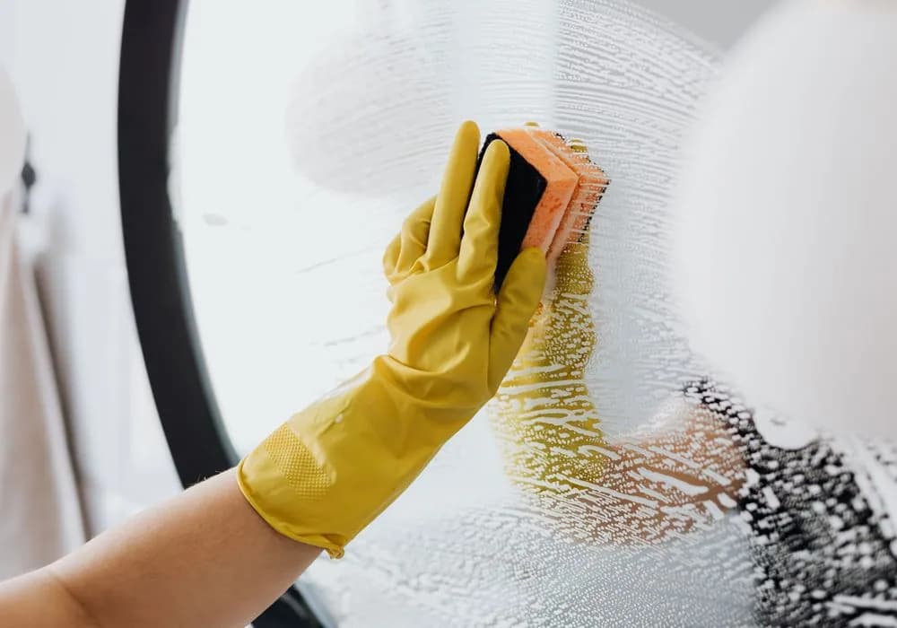 A gloved hand washing a glass window